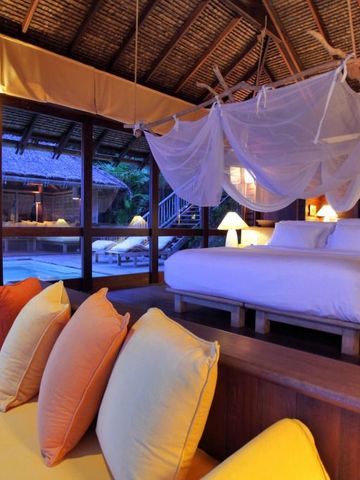 Luxuriöse Villa mit Himmelbett und Moskitonetz neben privatem Pool bei Sonnenuntergang