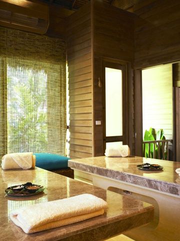 Spa-Behandlungsraum mit zwei Massagetischen und Blick auf tropische Vegetation