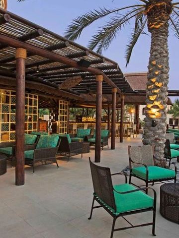 Terrasse mit gemütlichen Sitzbereichen und tropischer Bepflanzung.