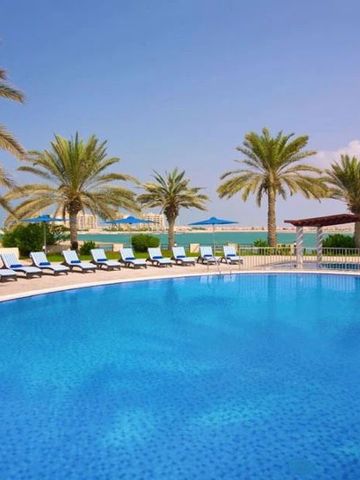 Weitläufiger Pool mit blauen Sonnenliegen und Palmen im Sofitel Al Hamra Beach Resort