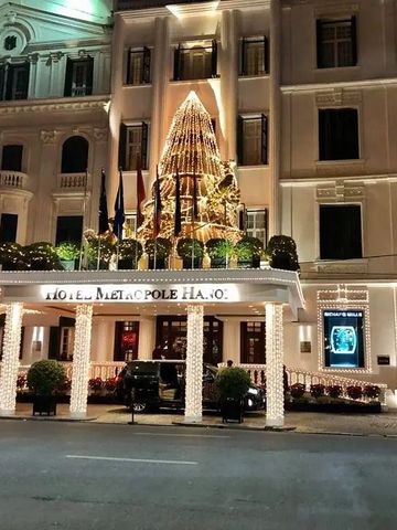 Beleuchteter Hoteleingang des Sofitel Legend Metropole Hanoi bei Nacht