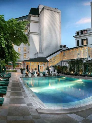 Outdoor-Poolbereich umgeben von modernen Gebäuden mit grünen Liegestühlen