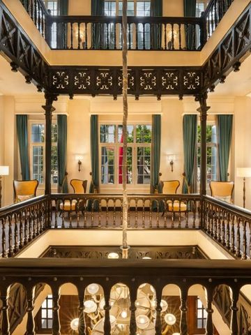 Historischer Innenbereich mit dekorativen Holzbalustraden und großem Kronleuchter