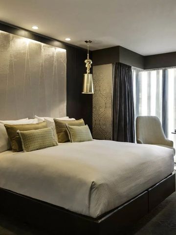 Elegant eingerichtetes Hotelzimmer mit einem großen Doppelbett und sanfter Beleuchtung.