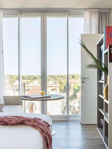 Helles Hotelzimmer mit Glasfront und Blick auf grüne Umgebung