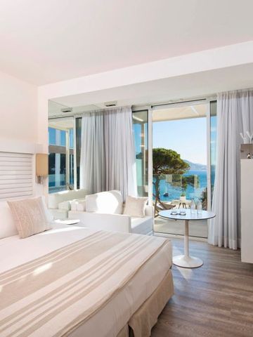 Helles Hotelzimmer mit großer Fensterfront und Meerblick.