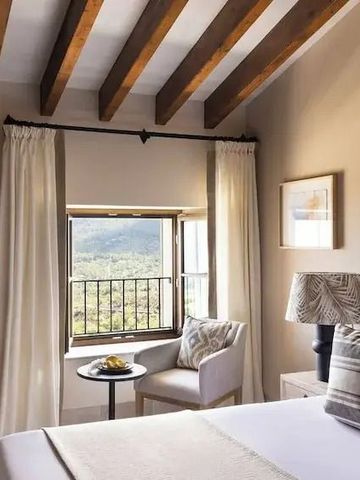 Helles Schlafzimmer mit Holzdeckenbalken und Ausblick auf die Natur