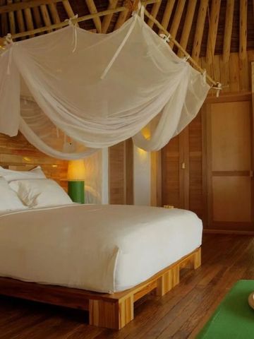 Geräumiges Schlafzimmer in einer Villa mit Himmelbett und naturbelassenen Holzelementen