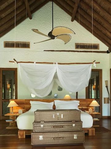 Geräumiges Schlafzimmer mit Himmelbett in einer Villa. Warme Holztöne und elegante Einrichtung.