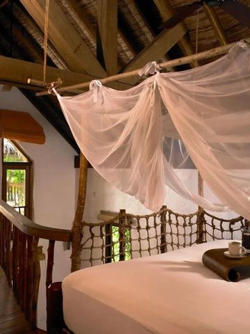 Romantisches Schlafzimmer mit Moskitonetz und gemütlichem Balkonblick ins Grüne.