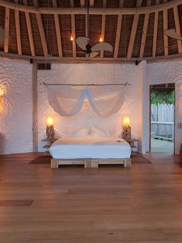 Offenes Schlafzimmer mit Himmelbett und mediterranen Holzwänden, helle Beleuchtung.