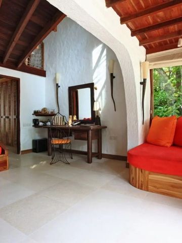 Helles Zimmer mit roten Kissen und Holzakzenten bei Soneva Fushi