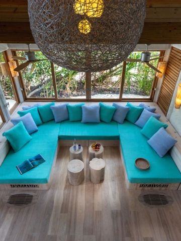 Lichtdurchflutete Lounge mit türkisfarbenen Sitzgelegenheiten im Soneva Jani Hotel