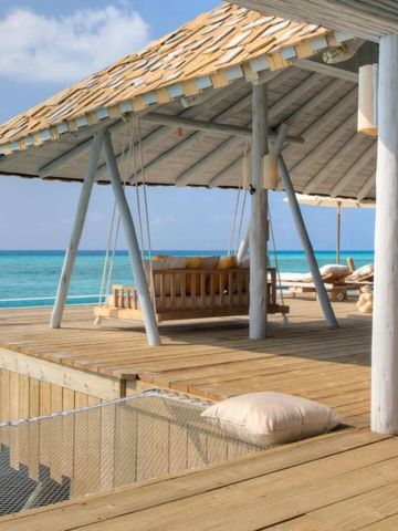 Überdachte Terrasse mit Schaukel über dem Ozean und blauem Himmel