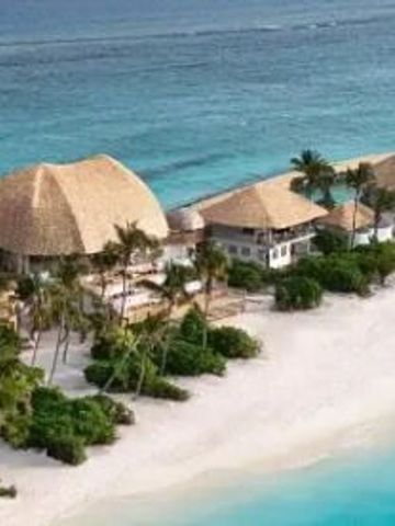 Luftaufnahme von Villen mit Strohdächern am weißen Sandstrand