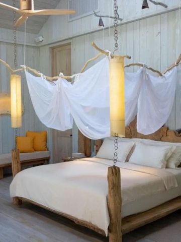 Luxuriöses Schlafzimmer mit rustikalem Holzdesign und weißen Stoffdrapierungen