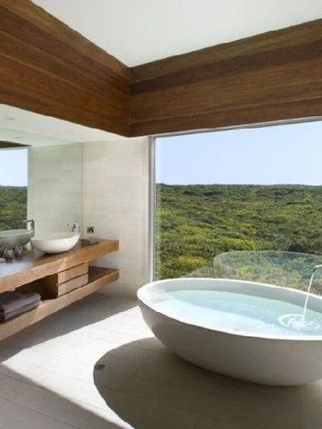 Luxuriöses Badezimmer mit freistehender Wanne und Panoramablick auf die Natur