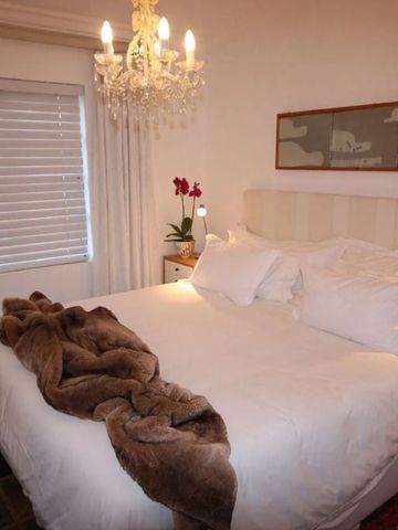 Elegantes Schlafzimmer mit Kronleuchter und Plüschdecke