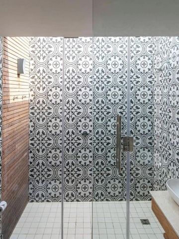 Modernes Badezimmer mit gemusterten Fliesen und Glasdusche