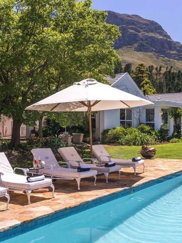 Pool mit Liegestühlen und Sonnenschirmen vor bergiger Kulisse
