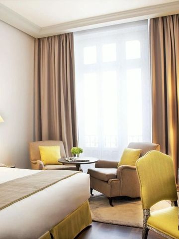 Helles Zimmer mit Kingsize-Bett, stilvollen Sesseln und Tageslicht.