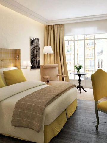 Zimmer mit Doppelbett, gelben Akzenten und Blick auf die Stadt.