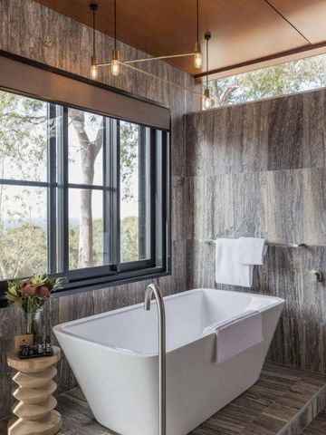 Elegantes Badezimmer mit frei stehender Badewanne und Fenstern