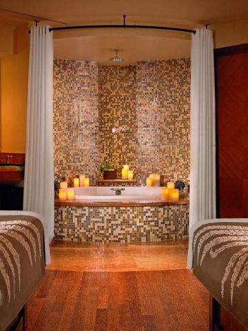 Wellnessbereich mit zwei Massagetischen und stimmungsvoller Beleuchtung.