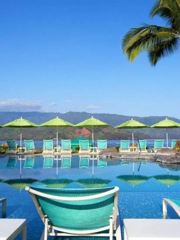 Poollandschaft mit Liegen und Sonnenschirmen vor Bergkulisse