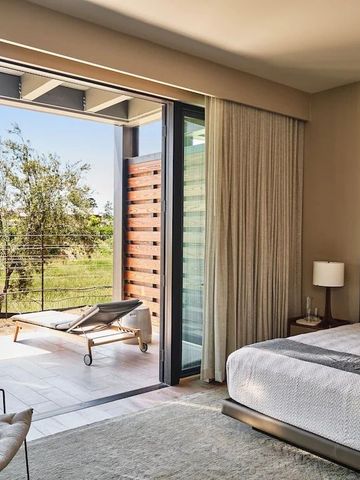 Helles Schlafzimmer mit Doppelbett und Terrasse mit grüner Landschaft