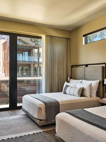 Doppelzimmer mit zwei Betten und großem Fenster mit Blick auf moderne Gebäude