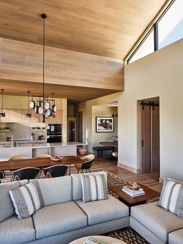 Elegantes Wohnzimmer mit Holzbalkendecke und moderner Küche im Hintergrund