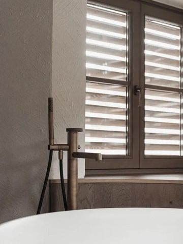 Luxuriöses Bad mit freistehender Wanne und Blick auf Fensterläden