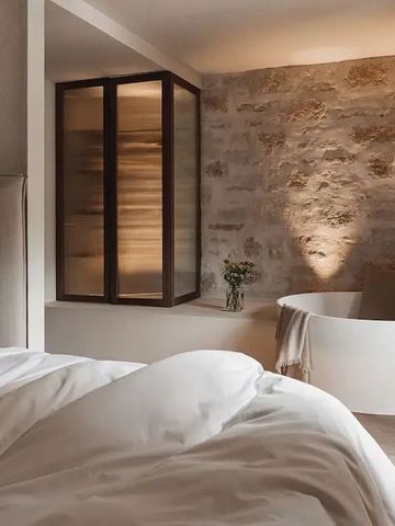 Hotelzimmer mit freistehender Badewanne und Steinwand.