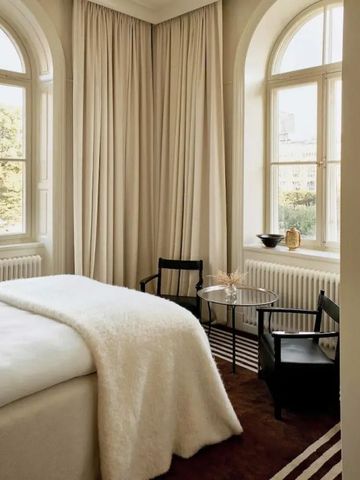 Helles Schlafzimmer mit großen Fenstern und eleganten Möbeln.