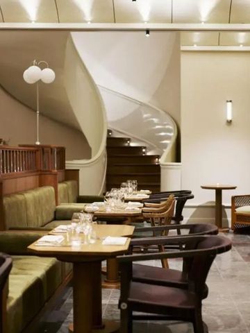 Elegantes Restaurant mit geschwungener Treppe und edlen Sitzbereichen.