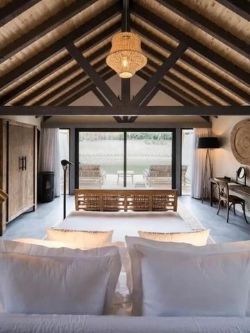 Geräumiges Schlafzimmer mit Holzbalkendecke und großer Fensterfront