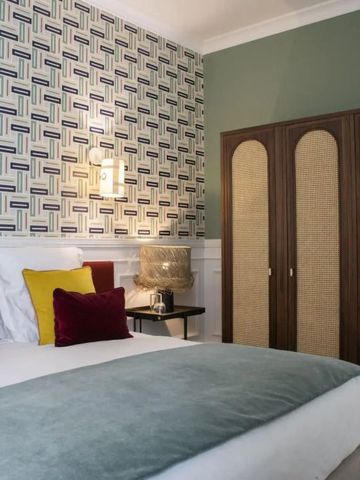 Gemütliches Doppelzimmer mit bunter Tapete und klassischem Schrank