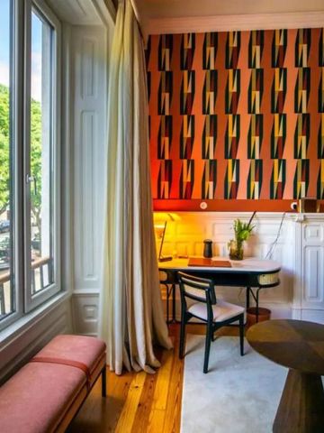Heller Sitzbereich mit Tisch und Stuhl neben großem Fenster und bunter Tapete