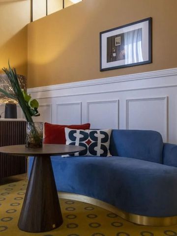 Luxuriöse Lounge mit blauer Sofagarnitur und stilvollen Details in warmen Farben