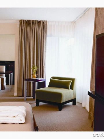 Modern eingerichtetes Hotelzimmer mit Sessel, Spiegel, großem Fenster