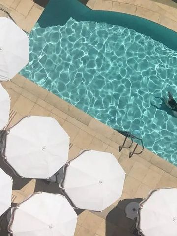 Sonnenliegen und Sonnenschirme an einem luxuriösen Pool.