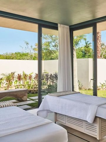 Spa-Raum mit zwei Massageliegen und Blick auf den Garten durch große Glaswände