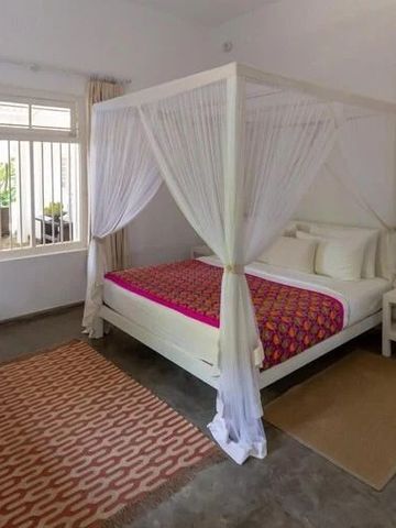 Schlafzimmer mit weißem Himmelbett und großen Fenstern