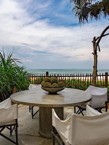 Terrasse mit Meerblick und großem Steintisch umgeben von tropischen Pflanzen