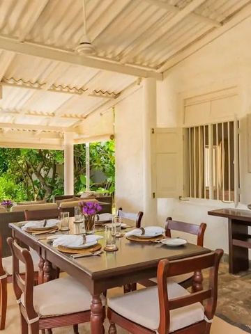 Überdachter Außenbereich mit Holztisch und Gartenblick