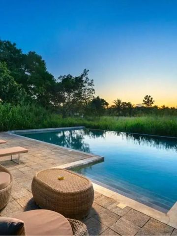 Infinity-Pool mit Sonnenliegen und Blick auf den Sonnenuntergang im Garten