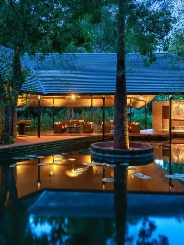 Abendaufnahme von beleuchtetem Pavillon mit Wasserreflexion im Teich