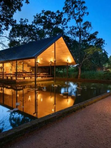 Außenansicht eines Gebäudes im Pavillon-Stil bei Dämmerung, umgeben von Wasser