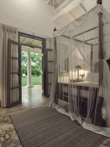 Offenes Schlafzimmer mit Himmelbett und Blick ins Grüne